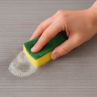 Mano che utilizza una spugna per pulire la Passatoia Cucina Genia Beige con schiuma di sapone.