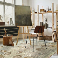 Tappeto Indoor Foglie in un ambiente moderno con una sedia, un tavolo da lavoro e un cavalletto.
