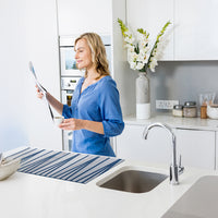 Donna in cucina con Passatoia Cucina Argento Vivo Blu, mentre legge una ricetta in un ambiente moderno.